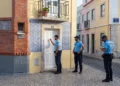 Immagine generata con tre poliziotti in una via a Lisbona mentre bussano alla porta di un affittacamere per verificarne la regolarità ed evitare una truffa.