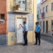 Immagine generata con tre poliziotti in una via a Lisbona mentre bussano alla porta di un affittacamere per verificarne la regolarità ed evitare una truffa.